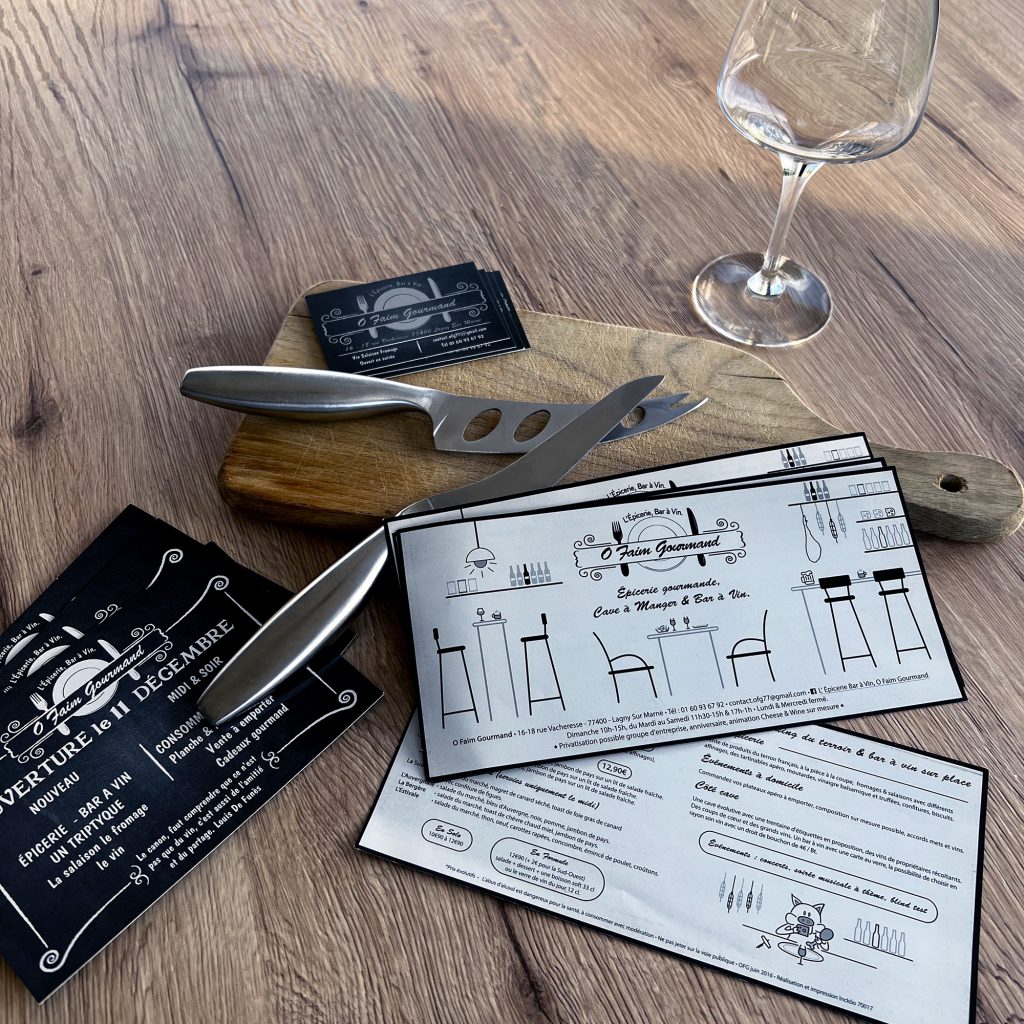 planche à découper, couteux et verre sur plan de travail en bois. Cartes de visite, flyer et menu O Faim Gourmand